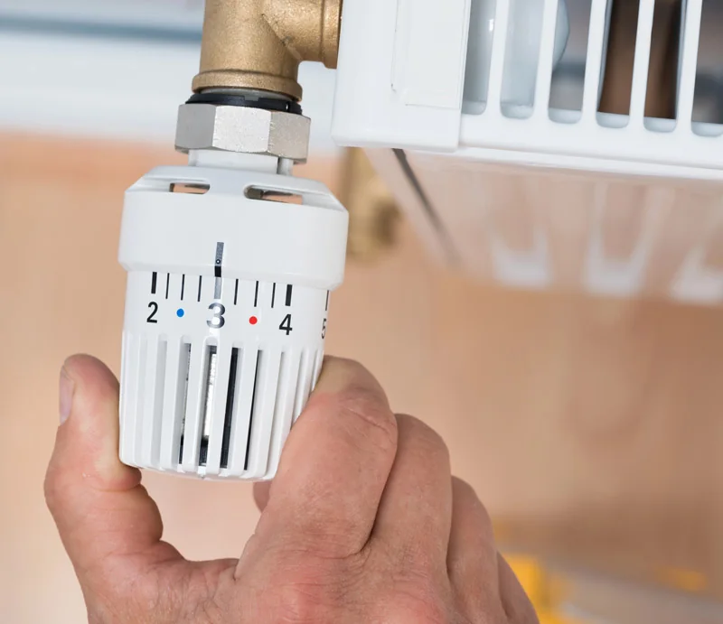Hand an einem Heizkörperthermostat